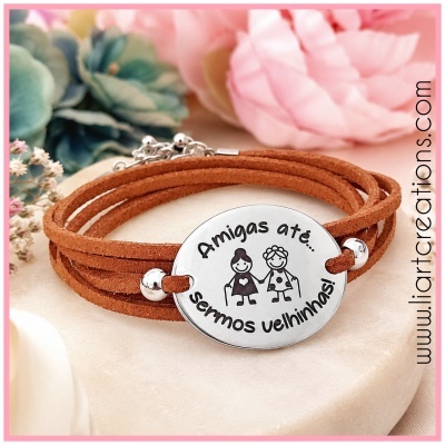 Pulseira de couro castanho com pendente metálico gravado e fecho em fundo com flores
