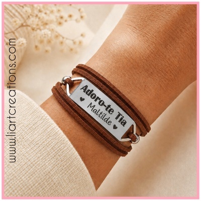 Pulseira de couro castanho com placa metálica prateada gravada com texto num pulso.
