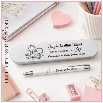 Estojo metálico cinza com texto personalizado para auxiliar Liliana e caneta branca numa mesa com itens de escritório cor-de-rosa e pastel.