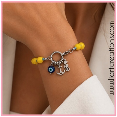 Pulseira com contas amarelas e pendentes metálicos no pulso de uma pessoa