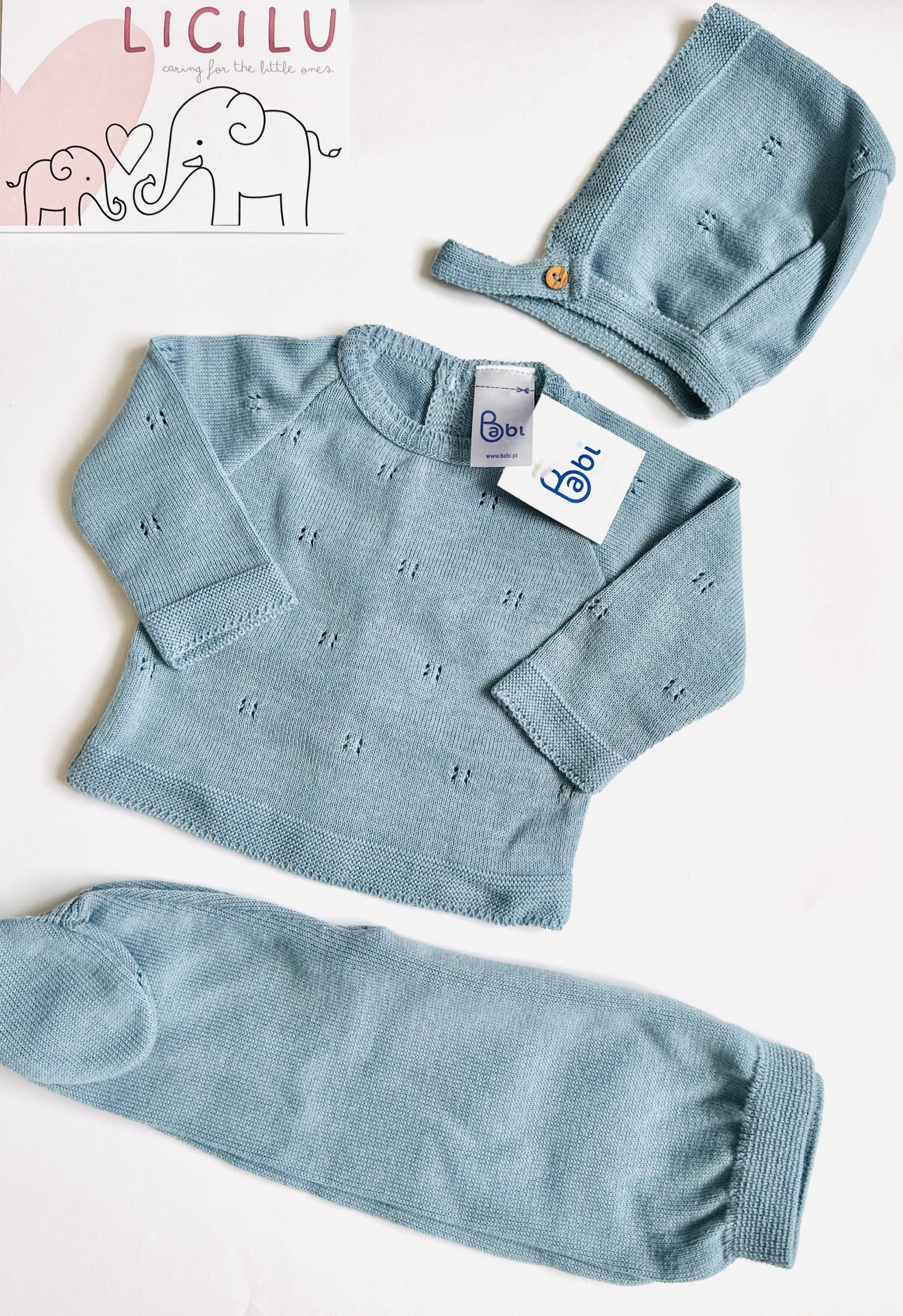 Conjunto de malha com calças e touca - Azul Conjunto de roupa azul claro para bebé com camisa, calças e gorro, etiqueta Babl e embalagem com desenho de elefantes