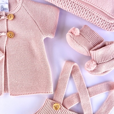 Conjunto rosa de roupa de bebé em malha com botões de madeira e pompons