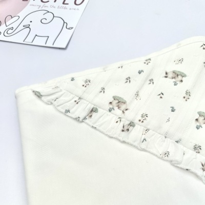 Roupa branca de bebé com padrão de coelhos e folhas e folho na borda