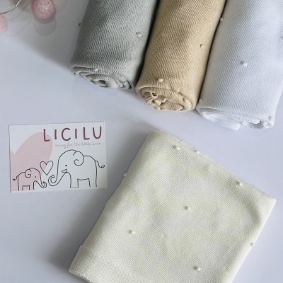 Mantas de bebé em quatro cores com pequenas bolinhas em relevo e cartão da marca LICILU
