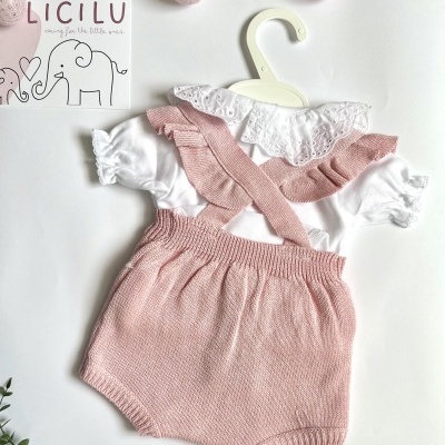 Conjunto de roupa de bebé com camisa branca e calções rosa em malha com alças, apresentado numa cabide.