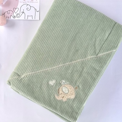 Manta verde clara riscada com bordado de elefante e cartão LICILU ao fundo