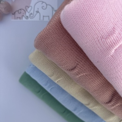 Cinco camisolas de malha em cores pastel dobradas com cartão LICILU e elefantes ao fundo