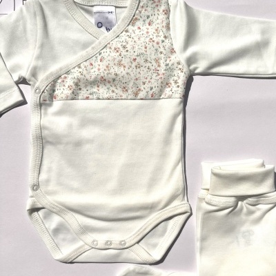 Body de bebé branco com padrão floral e leggings brancas com peúgas integradas.