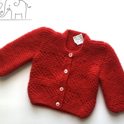 Casaco vermelho de bebé em fundo branco com decoração de elefantes na parede