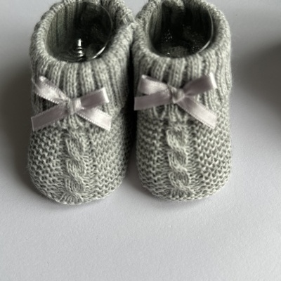 Sapatinhos de bebê em malha cinzenta com laços cor de rosa