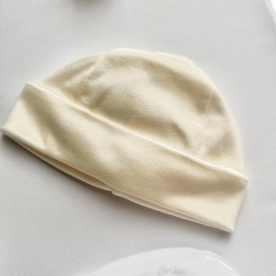 Gorro creme simples com aba dobrada sobre superfície branca