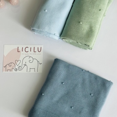 Três mantas de malha coloridas com pompons e cartão de marca