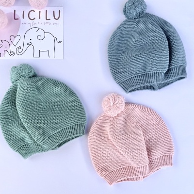 Três gorros de malha para bebé com pompom nas cores verde, rosa e cinza