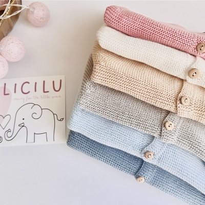 Camisas de malha infantis em cores suaves com botões de madeira, cartão com texto LICILU e desenhos de elefantes