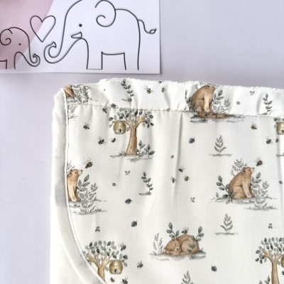 Fralda ou toalha branca com estampado de ursos e árvores e cartão com texto LICILU.