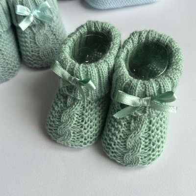 Sapatinhos de bebé verdes em malha com laços e padrão de trança