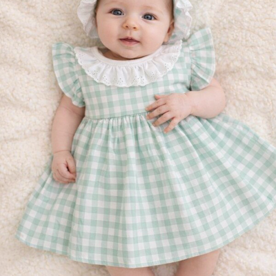 Bebé deitada com vestido xadrez verde e branco com gola rendada e chapéu igual