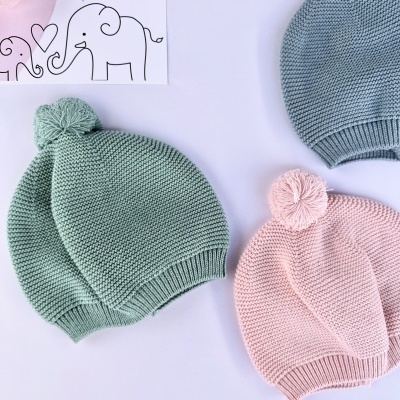 Três gorros de malha coloridos com pompom e placa com texto LICILU