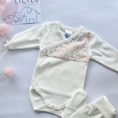 Conjunto de roupa de bebé branco com padrão floral e cartão LICILU ao lado