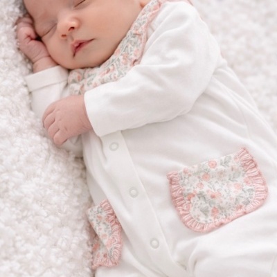 Bebé a dormir com fato branco e detalhes florais rosa e cinza