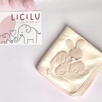Fralda bege com bordado de coelhos e cartão com texto LICILU e elefantes