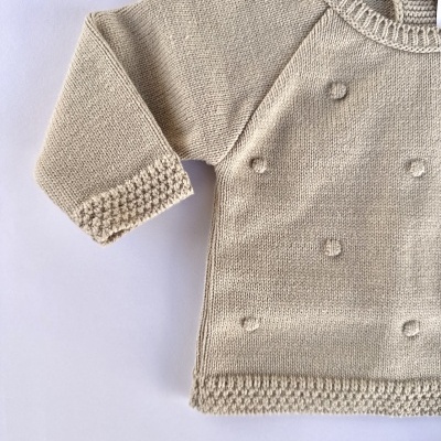 Camisola de malha bege clara com detalhes texturizados e acabamento decorativo