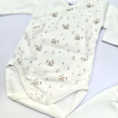 Body branco de bebé com padrão de animais e flores pequenas.