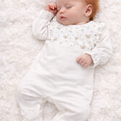 Bebé a dormir com macacão branco floral sobre manta branca