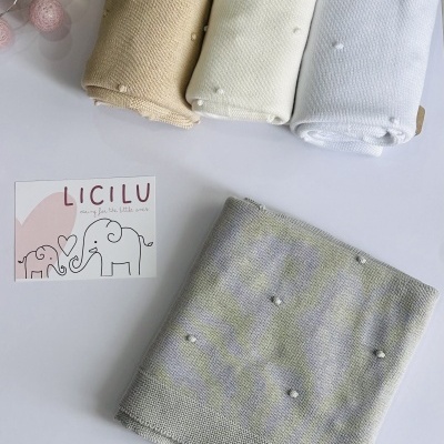 Mantinhas tricotadas bege, creme, branca e cinza com pompons brancos e cartão LICILU com elefantes