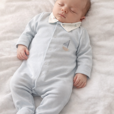 Bebé a dormir com macacão cinzento claro de barco bordado e gola branca, deitado em manta branca