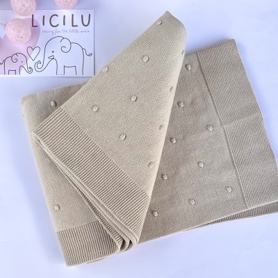 Cobertor bege com bolinhas texturizadas e cartaz com elefantes e texto LICLLU