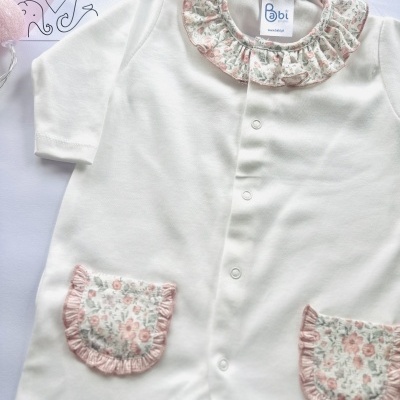 Macacão de bebé branco com gola e bolsos florais cor de rosa.