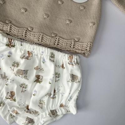 Conjunto para bebé com camisola bege de malha e calções brancos estampados