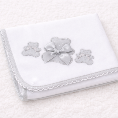 Fralda branca com ursinhos cinzentos e laço sobre fundo branco texturado