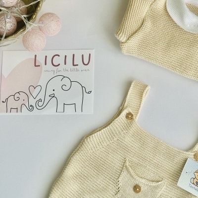 Roupa de bebê em malha bege claro com cartão da marca LICILU e luzes decorativas