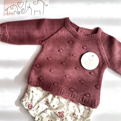 Conjunto de roupa de bebé com camisola rosa de malha e calções estampados com cogumelos.