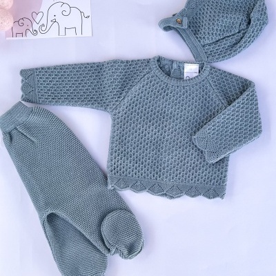 Conjunto de roupa de bebé azul com padrão de malha, incluindo gorro, camisola e calças com pezinhos, em fundo branco.