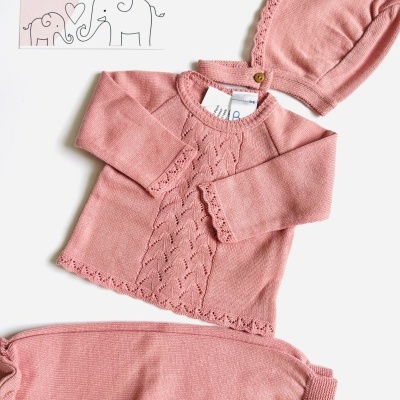 Conjunto de bebé rosa em malha com camisola, calças e touca com cartão ilustrativo da marca.