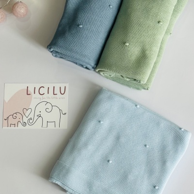 Três mantas de bebé coloridas em malha com pompons e cartão da marca Licilu
