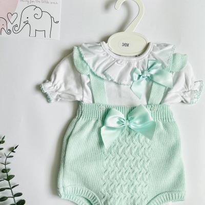Conjunto de roupa de bebé branco e verde água com gola franzida e calções de malha pendurado