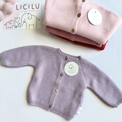 Casaco de malha lilás para bebé com botões, dois casacos dobrados rosa e vermelho e etiquetas com texto LICILU