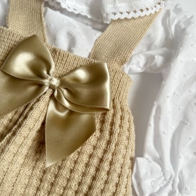 Conjunto infantil com camisola branca e jardineira bege de malha com laço dourado