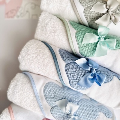 Toalhas infantis brancas com bordas coloridas e aplicações de ursinhos com laços de cetim.