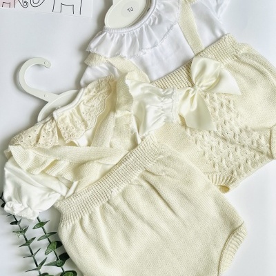 Roupa de bebé branca e bege clara com calções de malha e corpo com folho