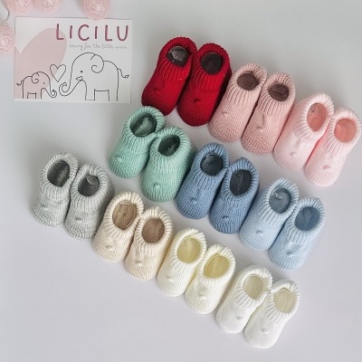 Sapatos de bebé tricotados de várias cores organizados sobre superfície cinza