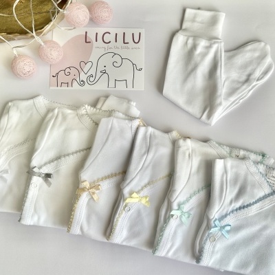 conjunto de bodies de bebé brancos com renda colorida, laços e calças brancas