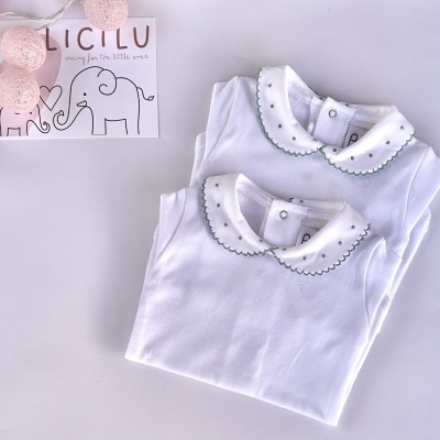 Dois bodies de bebé brancos com golas bordadas e cartão com elefantes e texto LICILU