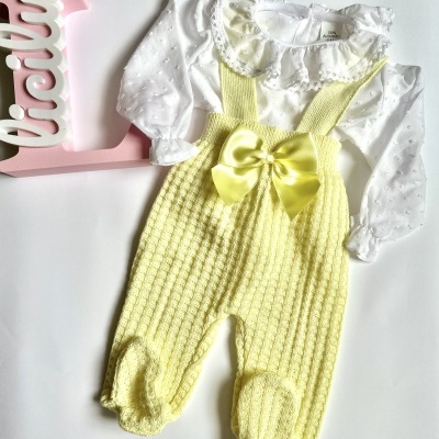 Conjunto de bebé branco com calças amarelas e laço, placa com nome Lúcia ao lado