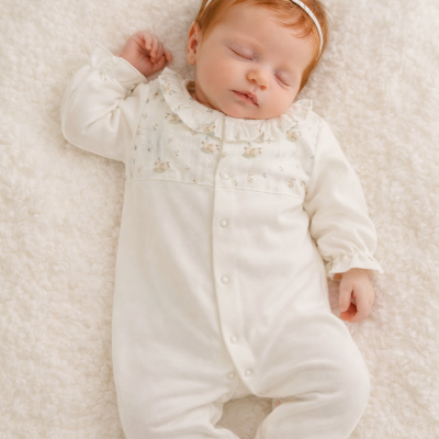 Bebé a dormir com babygrow branco e padrão floral