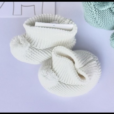 Sapatinhos de bebé brancos em tricô com pompons pequenos